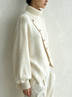 Ivory turtleneck sweater showing the dropped shoulders and wide sleeves