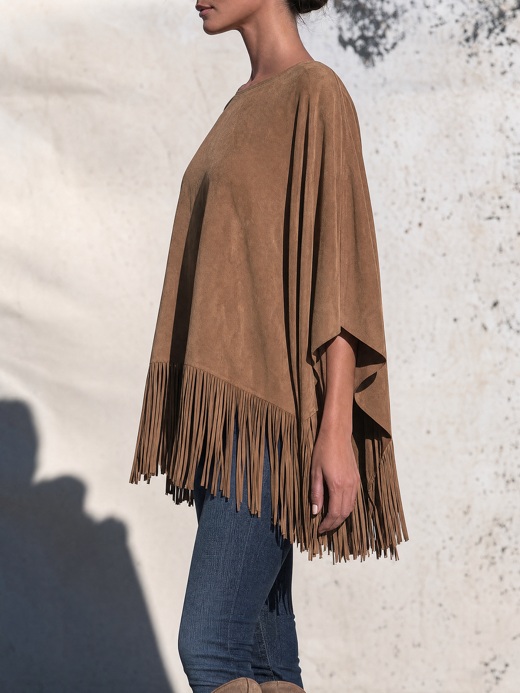Tan fringe poncho styled loose over jeans, side view