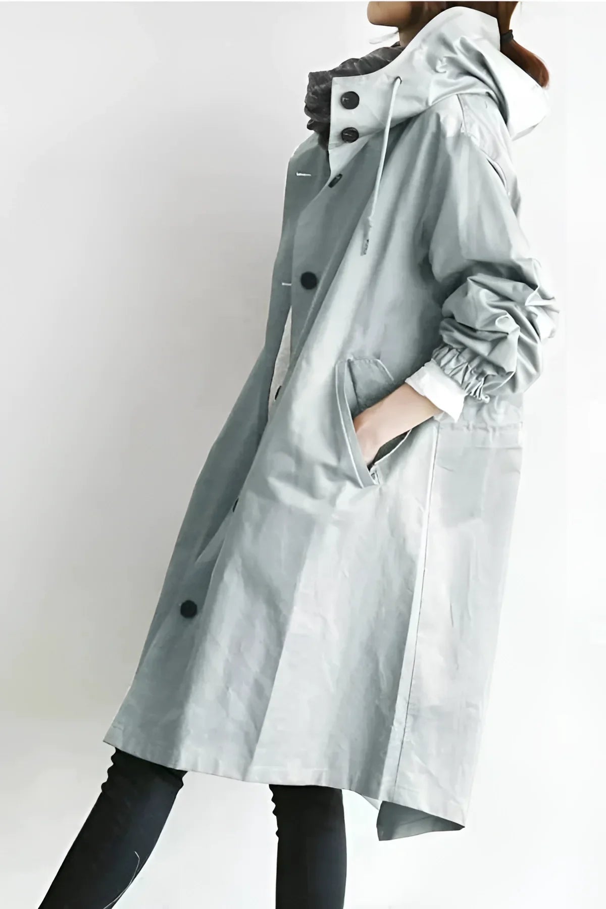 Waterproof hooded raincoat worn open over a sweater, side view